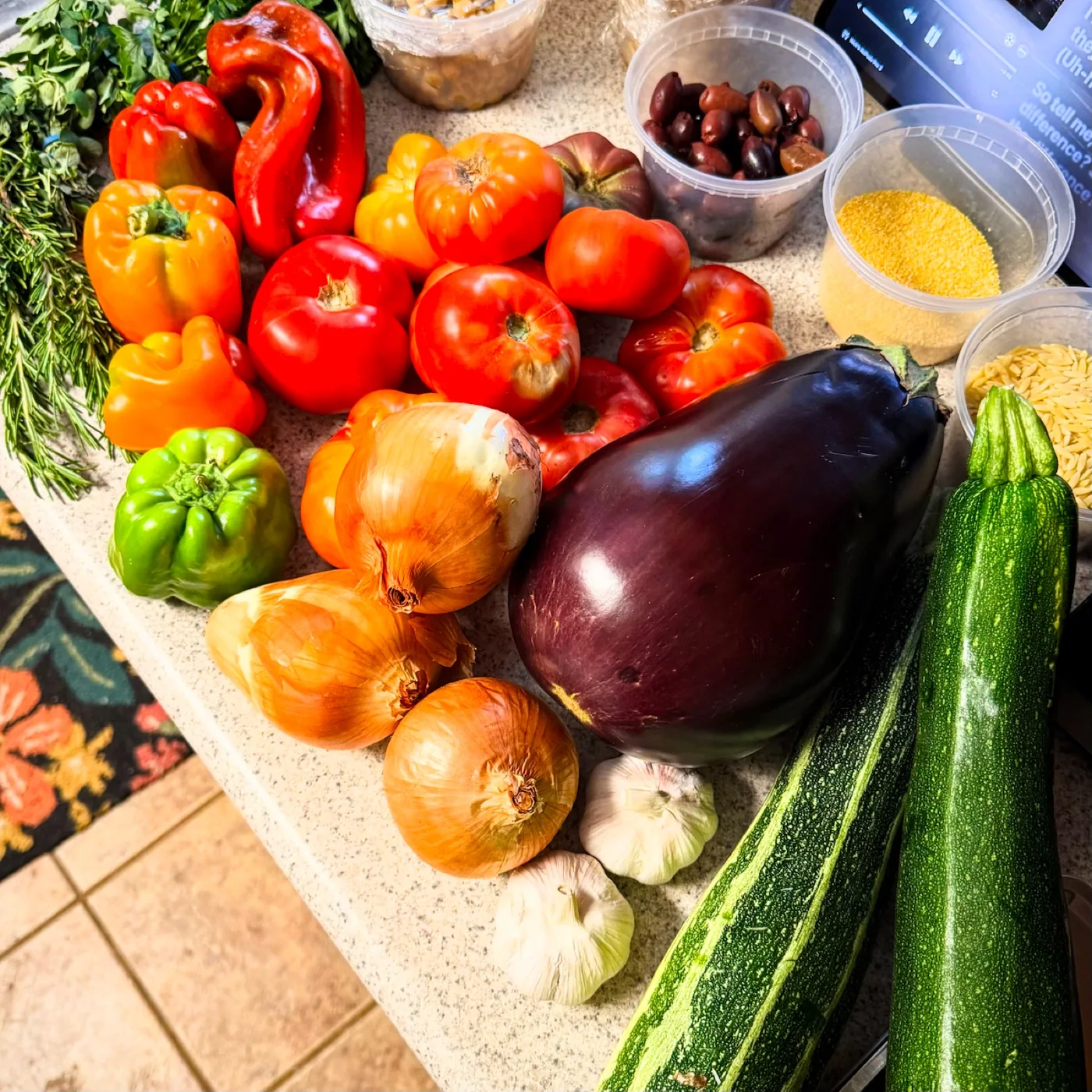 Summer tomatoes, peppers, eggplant, zucchini, onions, garlic, herbs, and pantry ingredients ready for meal preparation