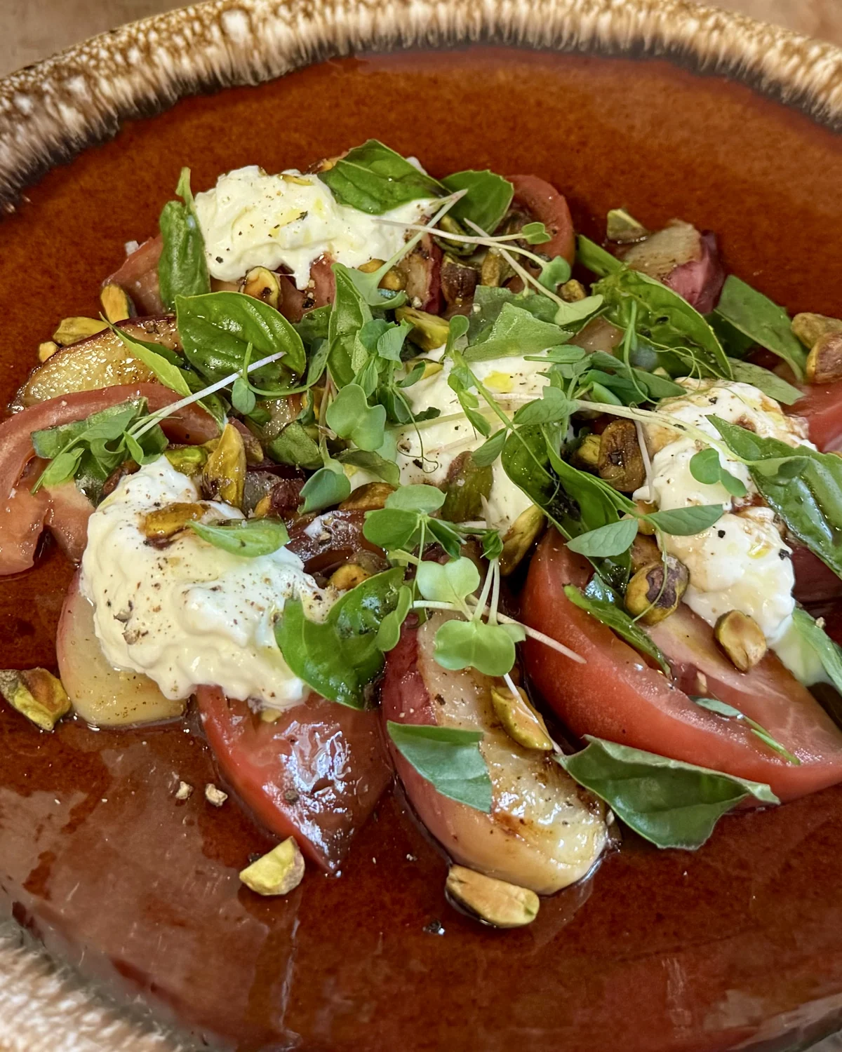 Seasonal tomatoes and burrata with fresh herbs and pistachios